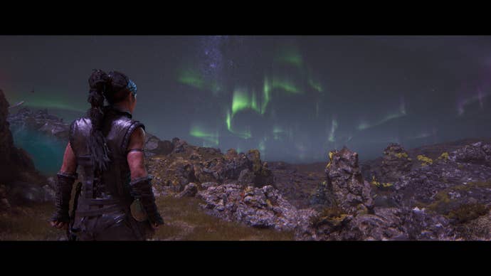 Senua, in Hellblade 2, stares out across the Icelandic scenery to watch the aurora borealis.